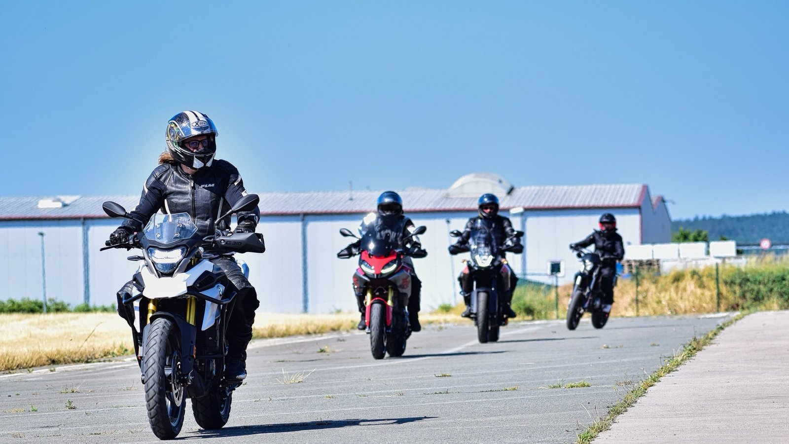 Vier Motorradfahrer in Formation auf dem Trainingsgelände, alle in voller Schutzkleidung