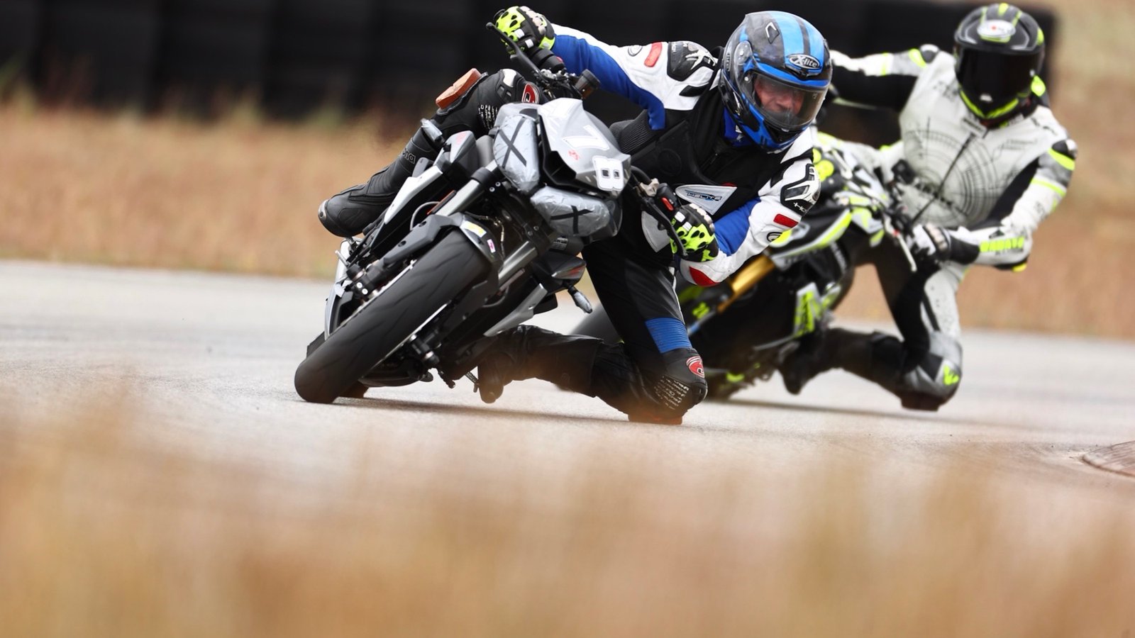 Zwei Motorradfahrer in tiefer Schräglage hintereinander, beide in voller Schutzkleidung